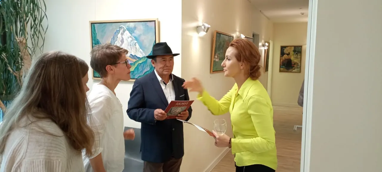 Alejandro Galindo conversa con dos visitantes ante un paisaje andino