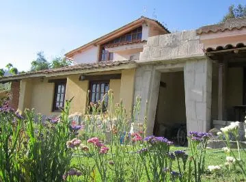 Casa con muros de piedra y un jardín de flores delante