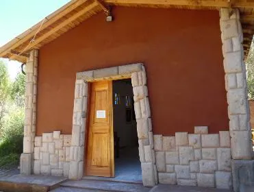 Casa de paredes de tierra ocre con la portada y el zócalo de piedra labrada