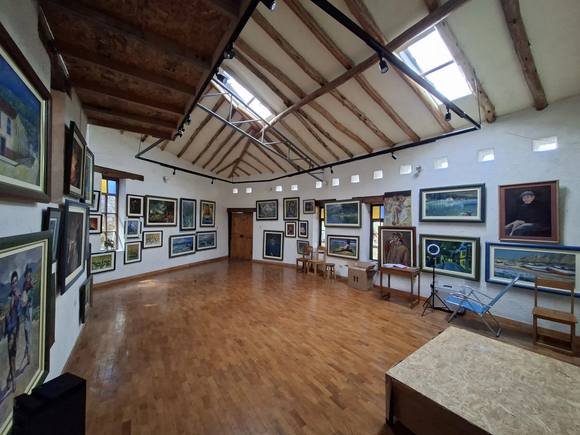 La sala de la galería vista desde el otro extremo, con los cuadros en las paredes y un caballete