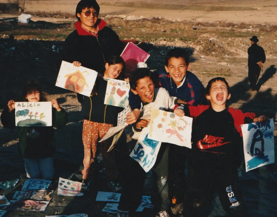 Un grupo de niños enseña sus dibujos a la orilla de un río